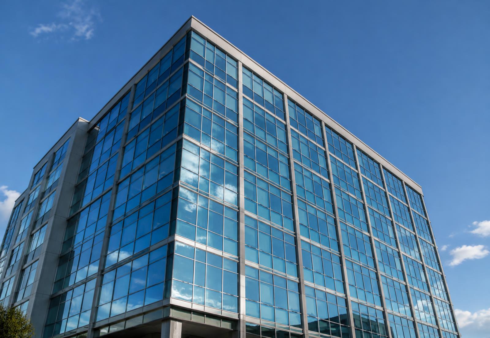 Mid-rise commercial building with a grid of glass windows against a blue sky